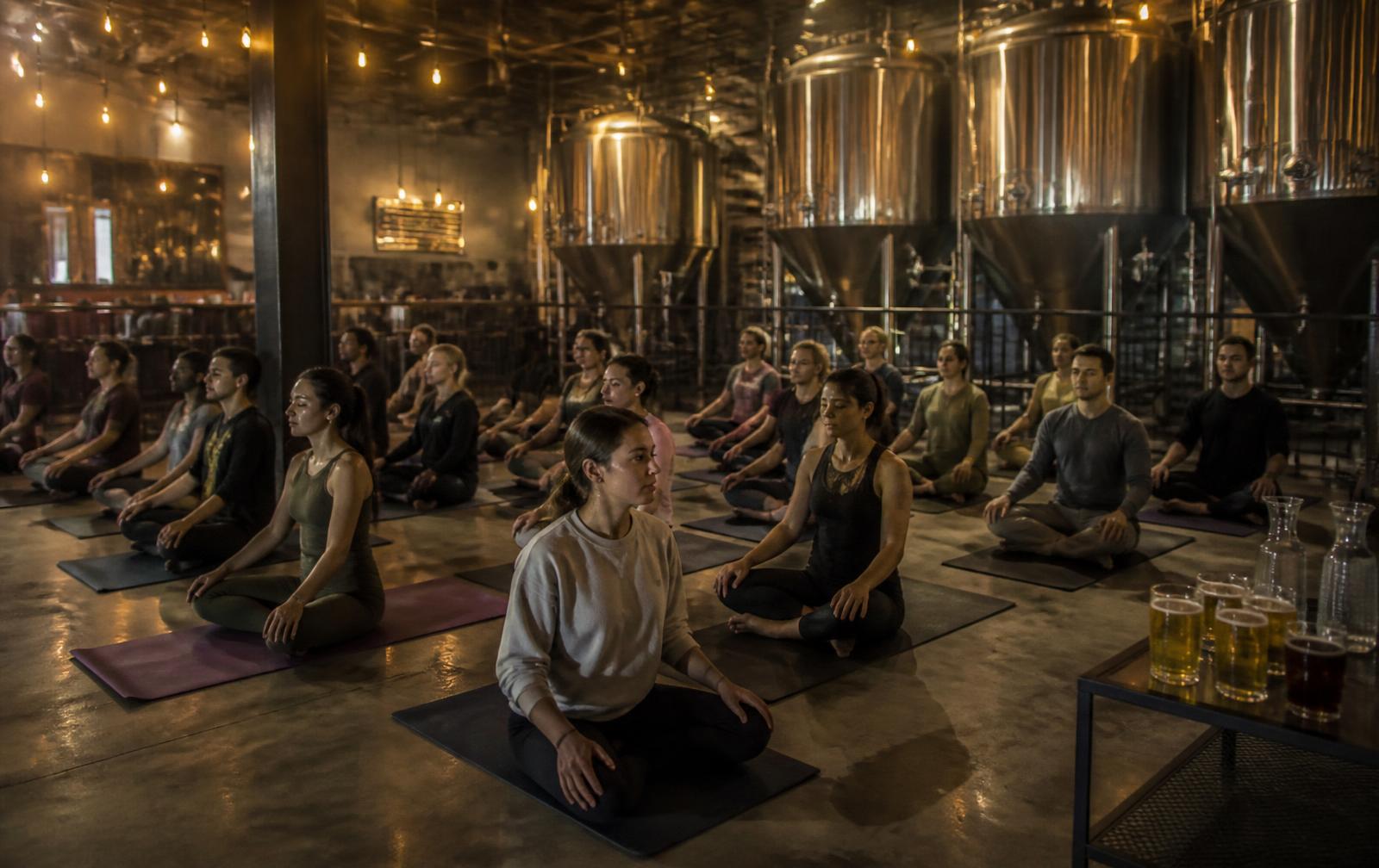 Séance intimiste dans une brasserie artisanale : adultes assis sur des tapis devant des cuves de fermentation.